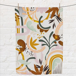 Colorful abstract patterned tea towel hanging on a line against a white brick wall.