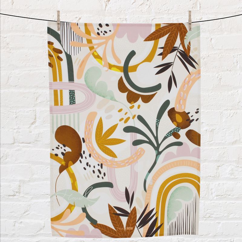 Colorful abstract patterned tea towel hanging on a line against a white brick wall.